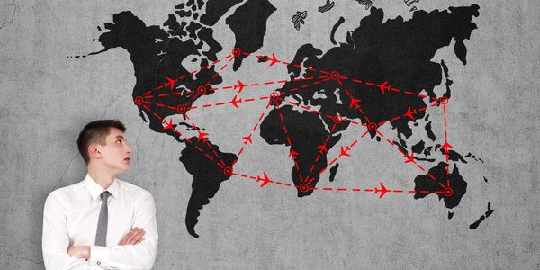 Businessman looking at a world map with red flight route connections.
