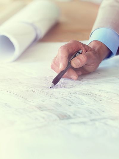 Person pointing at architectural plans with a pen.