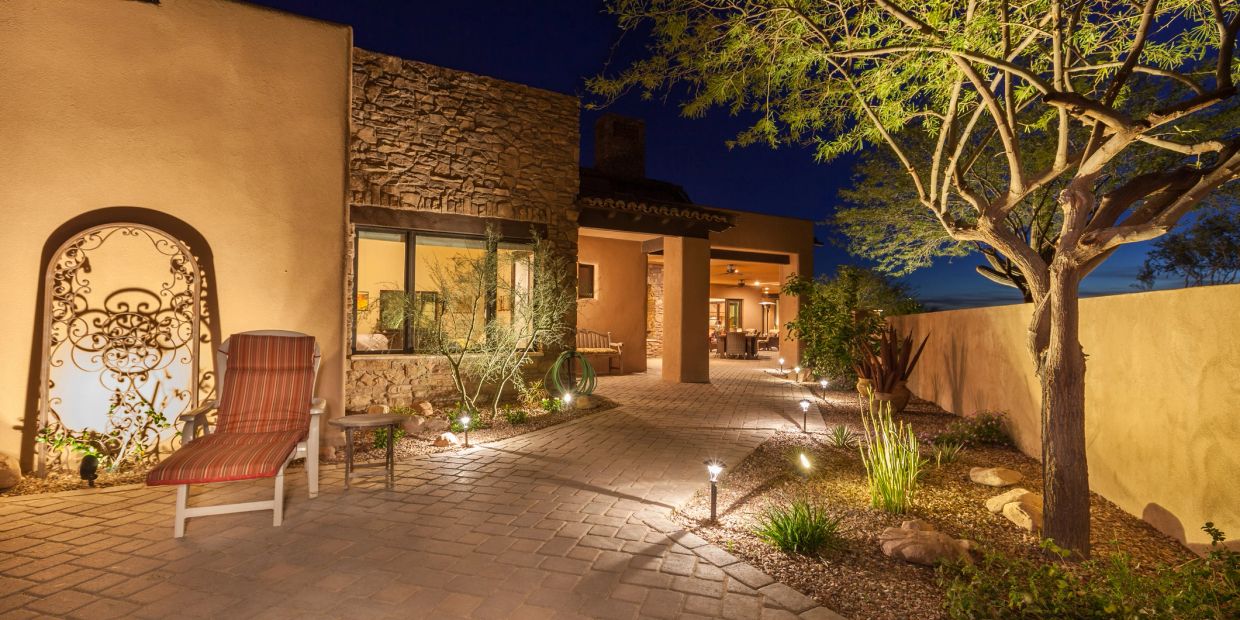 Well-lit outdoor patio with stone walls and garden lights at night.