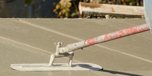Concrete being smoothed with a finishing trowel on a construction site.