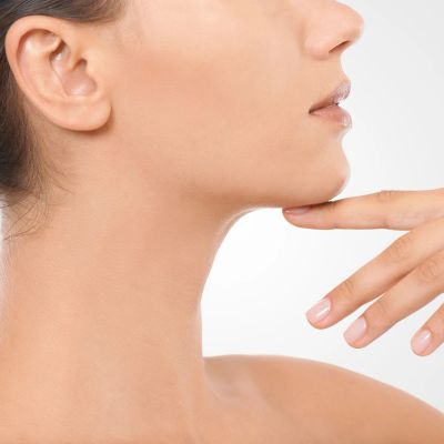 Close-up of a woman's neck and jawline with her finger gently touching her chin.