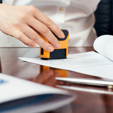 Hand stamping a document on a desk.
