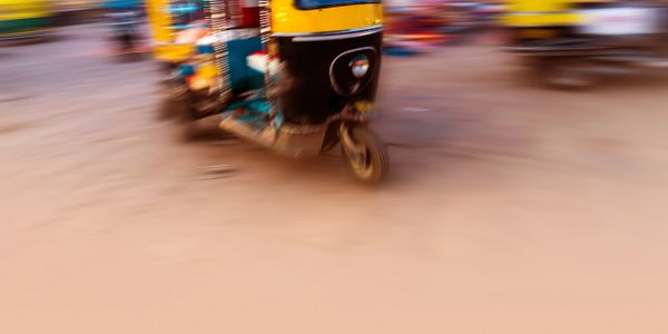 Blurred auto-rickshaw in motion on a city street.