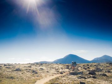 Cyclist riding on a rocky trail under the sun.