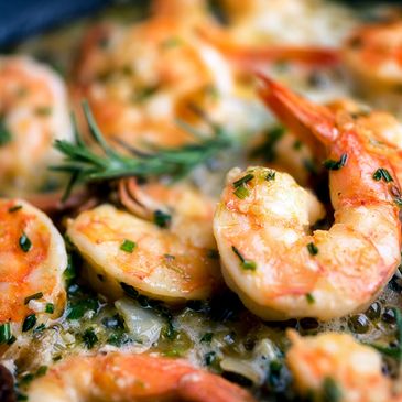 Close-up of cooked shrimp with herbs and garlic butter sauce.