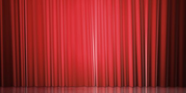 Closed red theater curtains on a stage.