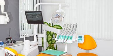 Modern dental clinic with orange chairs and advanced equipment.