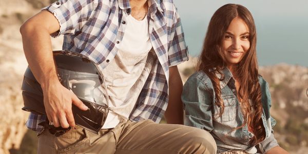 Young couple enjoying a sunny day outdoors with a motorcycle helmet.