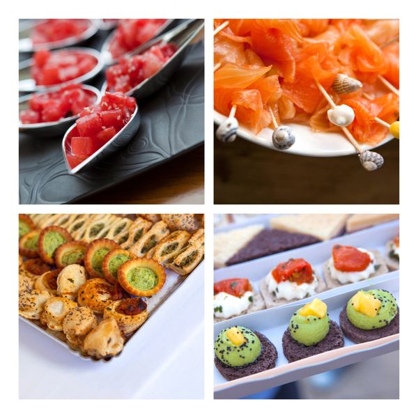 Assorted elegant appetizers including salmon, pastries, and colorful bites on trays.