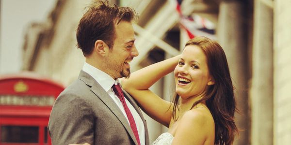 Happy couple embracing near a British red phone booth with Union Jack flags.