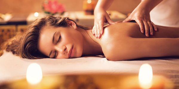 A woman enjoys a relaxing back massage in a serene spa setting.