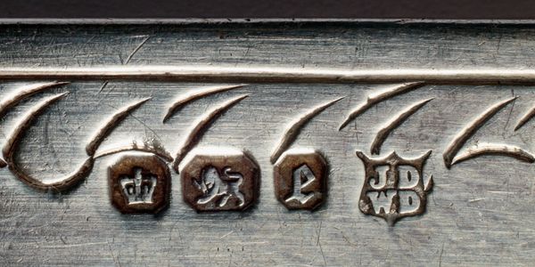 Close-up of hallmark stamps on a metal surface with intricate engraving.