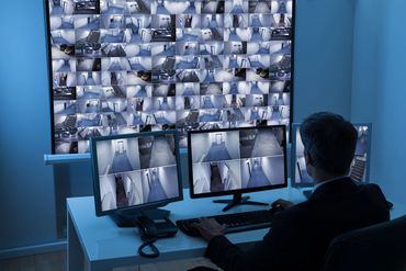 Person monitoring multiple security camera feeds.