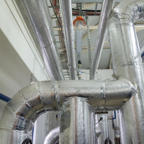 Insulated metallic pipes in an industrial setting.