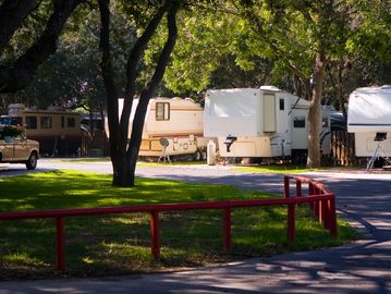 Parked RVs in a shaded campground area.