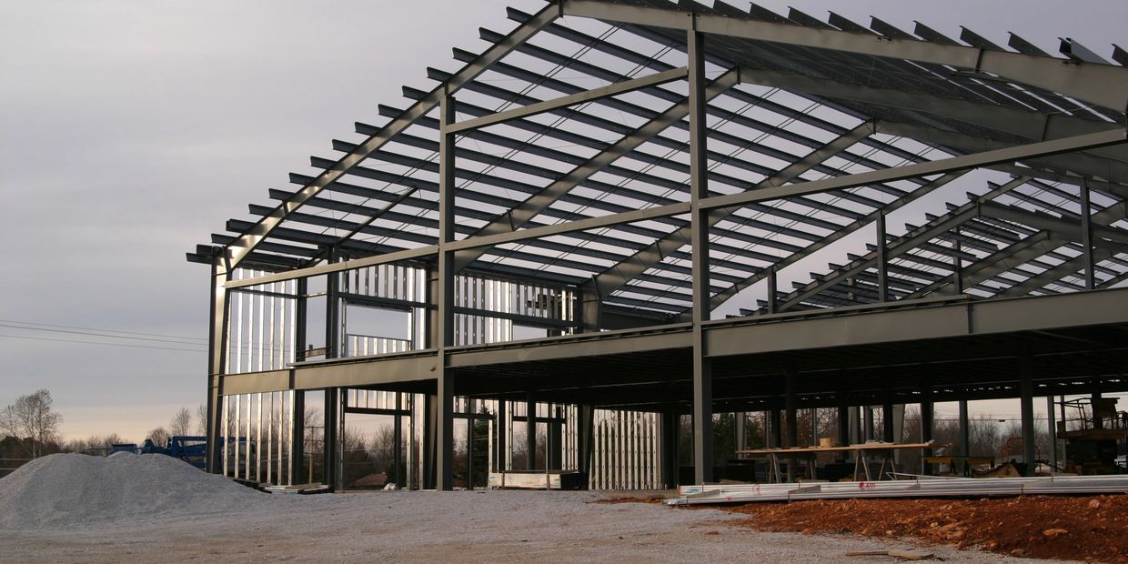 Steel frame structure of a building under construction on a cloudy day.