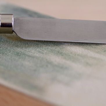 Close-up of a woodworking chisel on a sanding block.