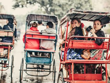 People riding rickshaws on a rainy day.