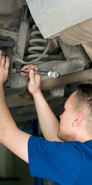 Cars lifted in a garage with focus on a tire.
