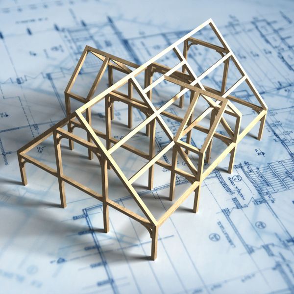 Wooden architectural model on blueprints showing a building framework.