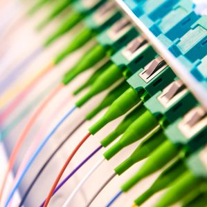 Close-up of fiber optic cables plugged into a network panel.