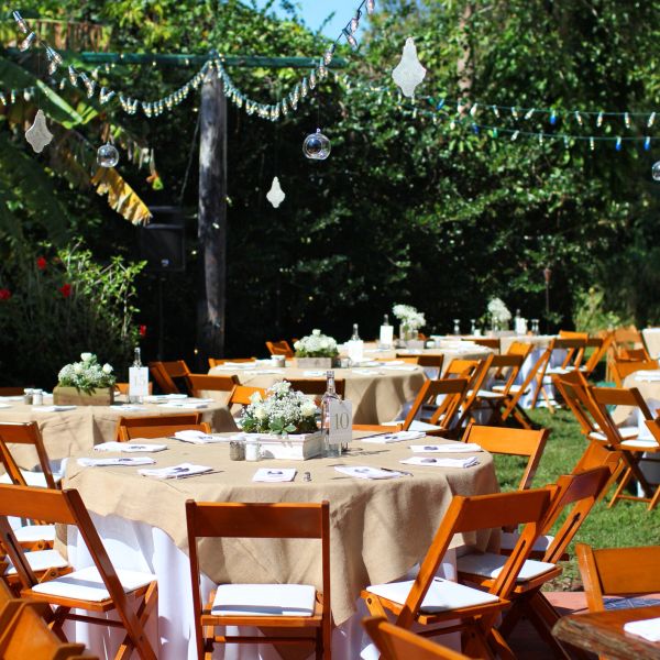 Outdoor garden party setup with decorated tables and wooden chairs.