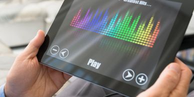 Person holding a tablet playing music with colorful equalizer display.
