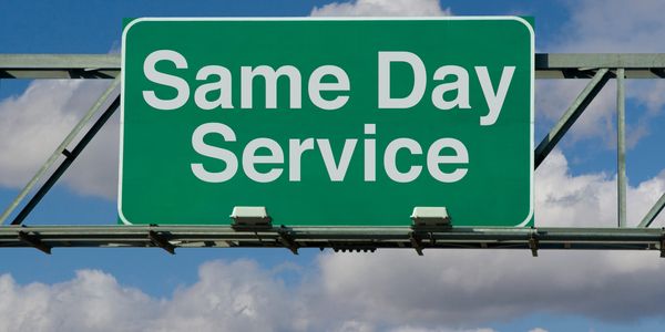 Green signboard displaying 'Same Day Service' against a blue sky.