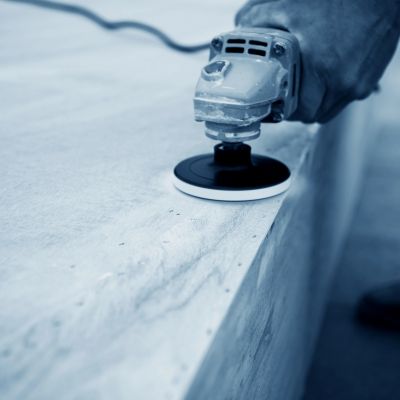 Close-up of a hand-held power sander smoothing a concrete surface.
