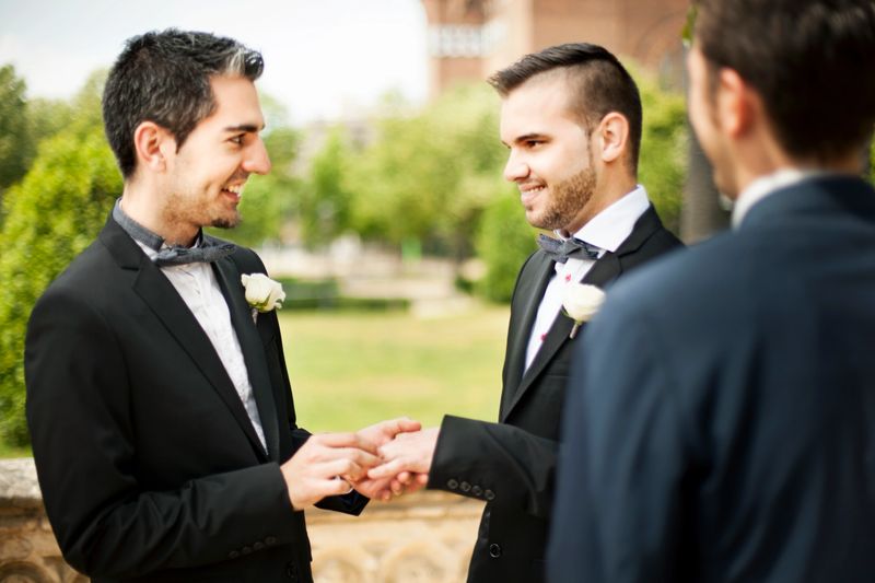 Man placing ring on groom's finger during wedding ceremony