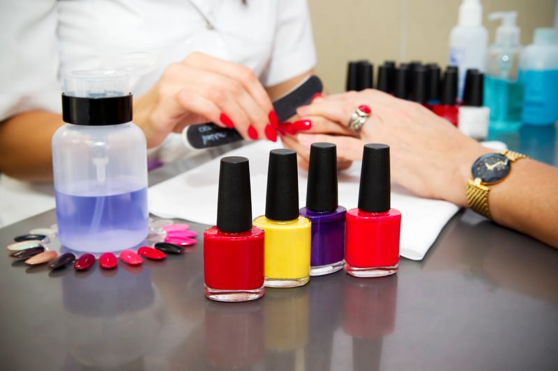 Manicure at the beauty salon. Multi-colored nail polish. Beautiful female hands.