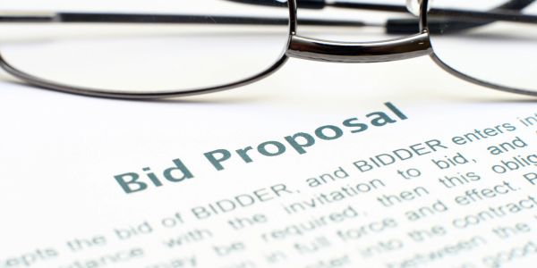 Close-up of a bid proposal document with eyeglasses.
