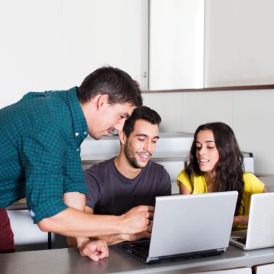 Three students collaborating on a laptop.