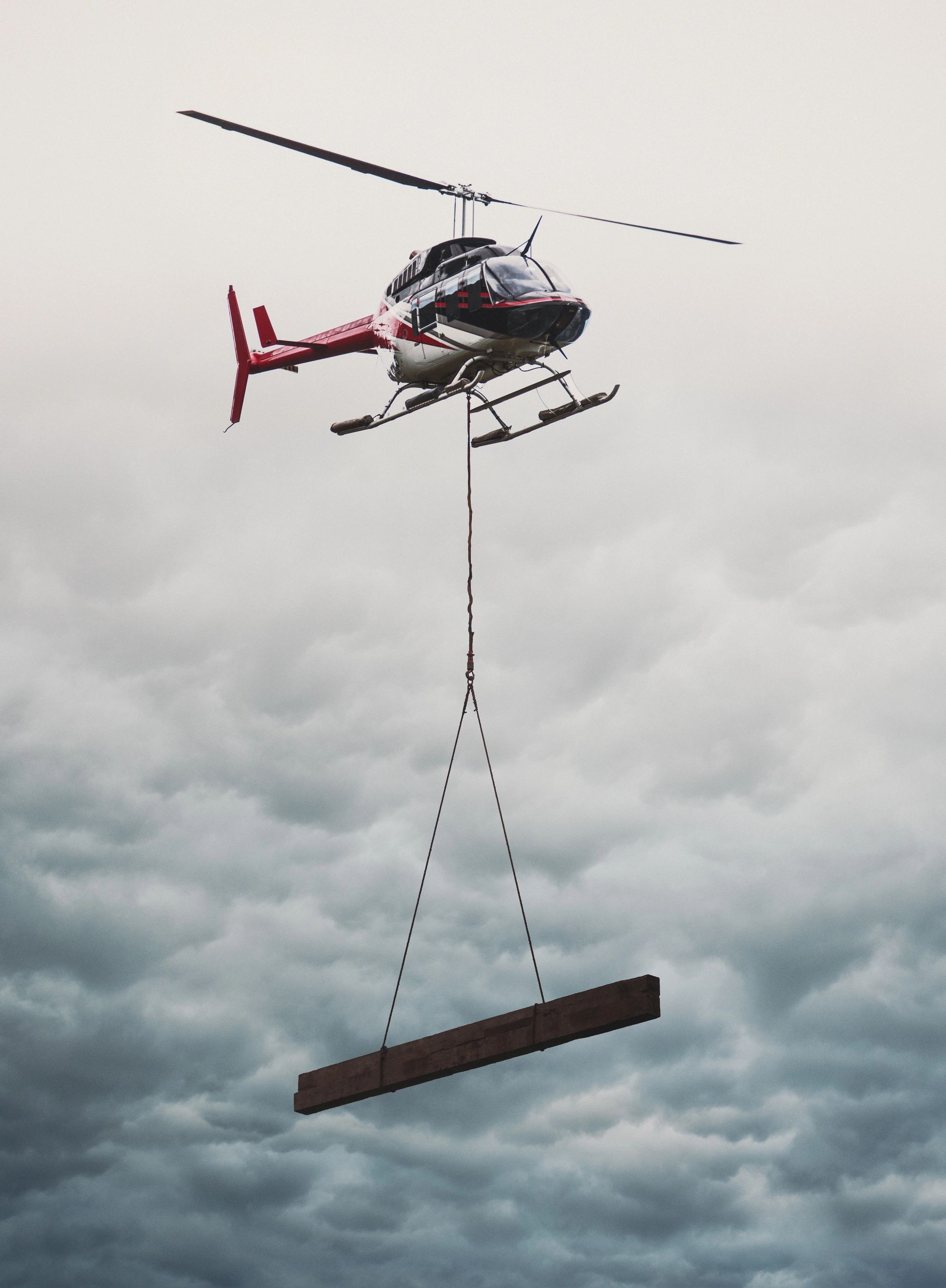 Helicopter transporting a large wooden beam.