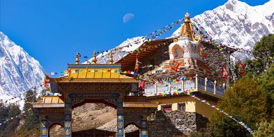 Colorful Nyingmapa monastery with prayer flags in the Himalayas under a clear blue sky.