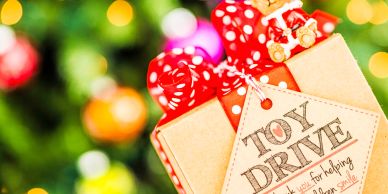 Gift boxes with a toy drive tag in front of a Christmas tree.