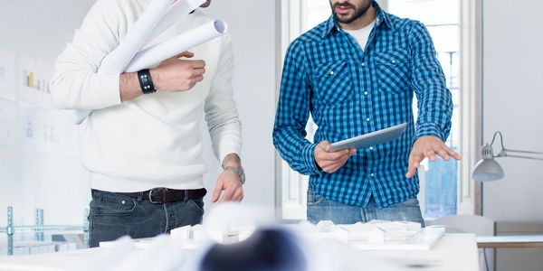 Two men discussing architectural plans with blueprints and models.