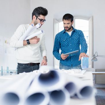 Two men discussing architectural plans with blueprints.