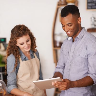 Two people happily discussing something on a tablet.