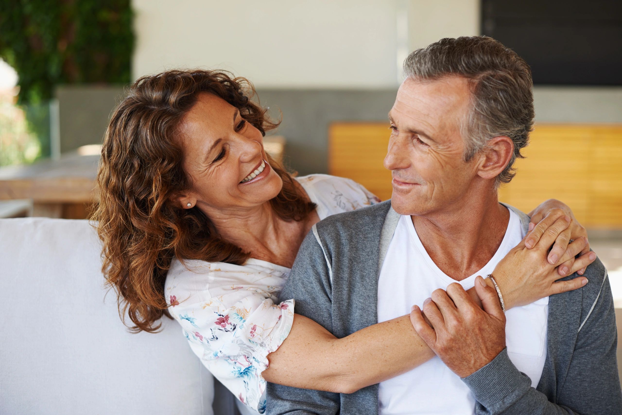Smiling middle-aged couple embracing affectionately indoors.