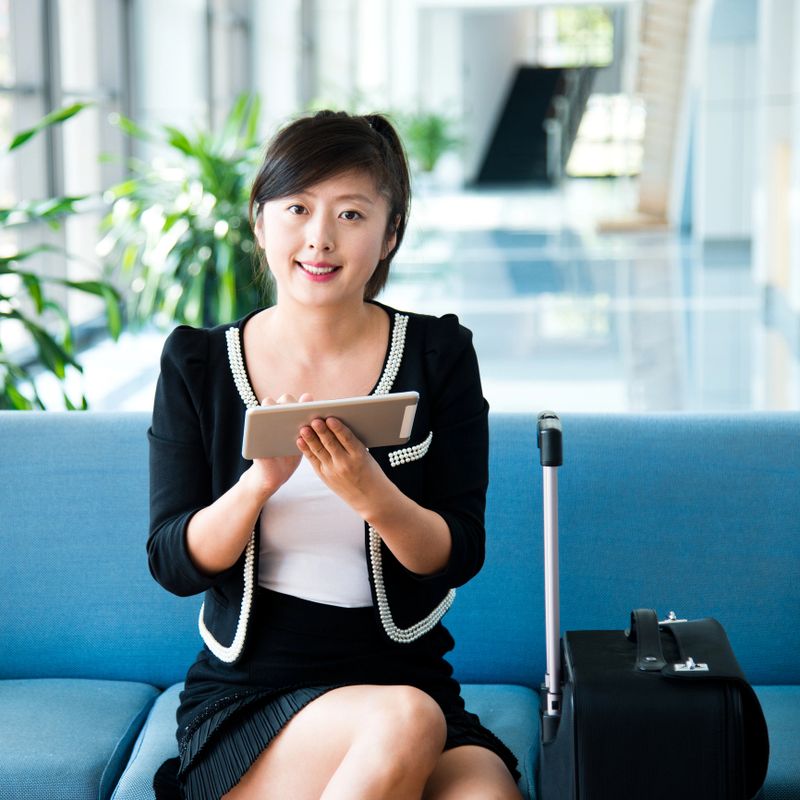 Businesswoman sitting at the airport departure lounge, using tablet