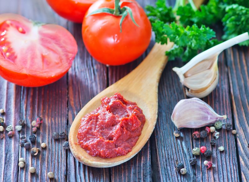tomato sauce in wooden spoon and on a table
