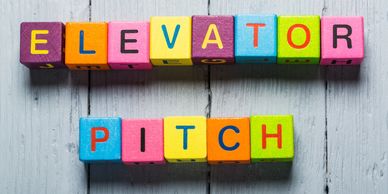 Colorful blocks spelling 'ELEVATOR PITCH' on a gray wooden surface.