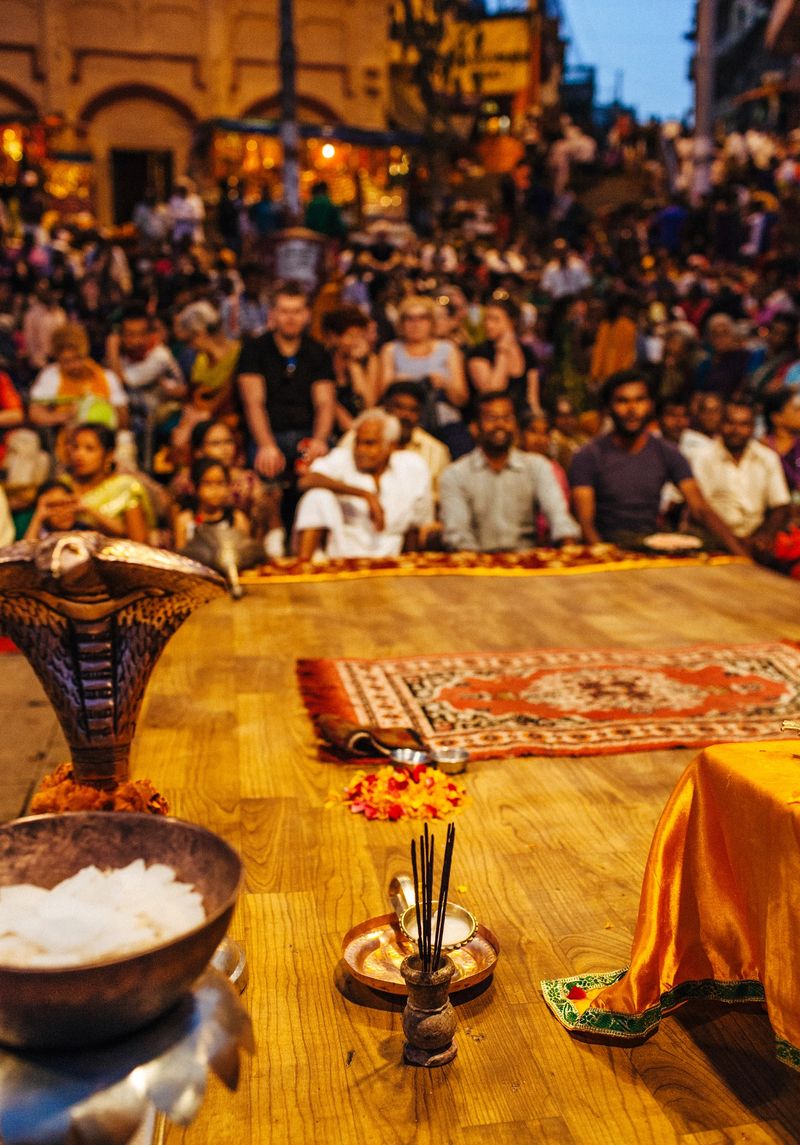 Varanasi's Ganga Aarti is a public religious ritual honoring Lord Shiva, which takes place next to the Ganges every evening at the holy Dasaswamedh, one of the river ghats. In the background, people are seen seated on the ground.