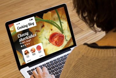 Person browsing a cooking blog about cheesy shortcakes on a laptop.