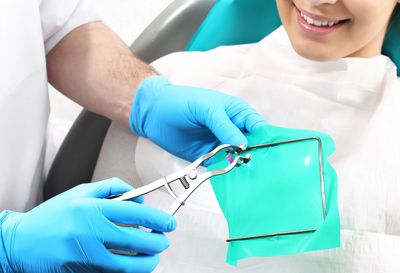 Dentist prepares dental dam for patient during treatment.