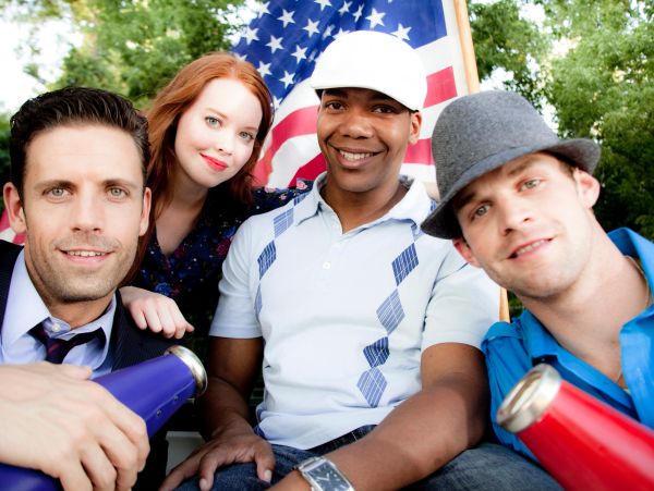 Group of diverse friends posing with American flag.