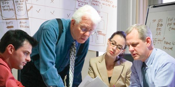 Four professionals engaged in a focused discussion around documents in an office.