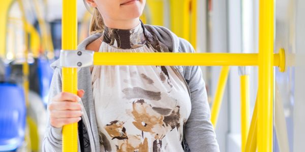 Woman holding a yellow pole inside a public bus.