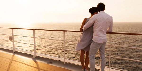 Couple embracing and watching the sunset on a ship deck.